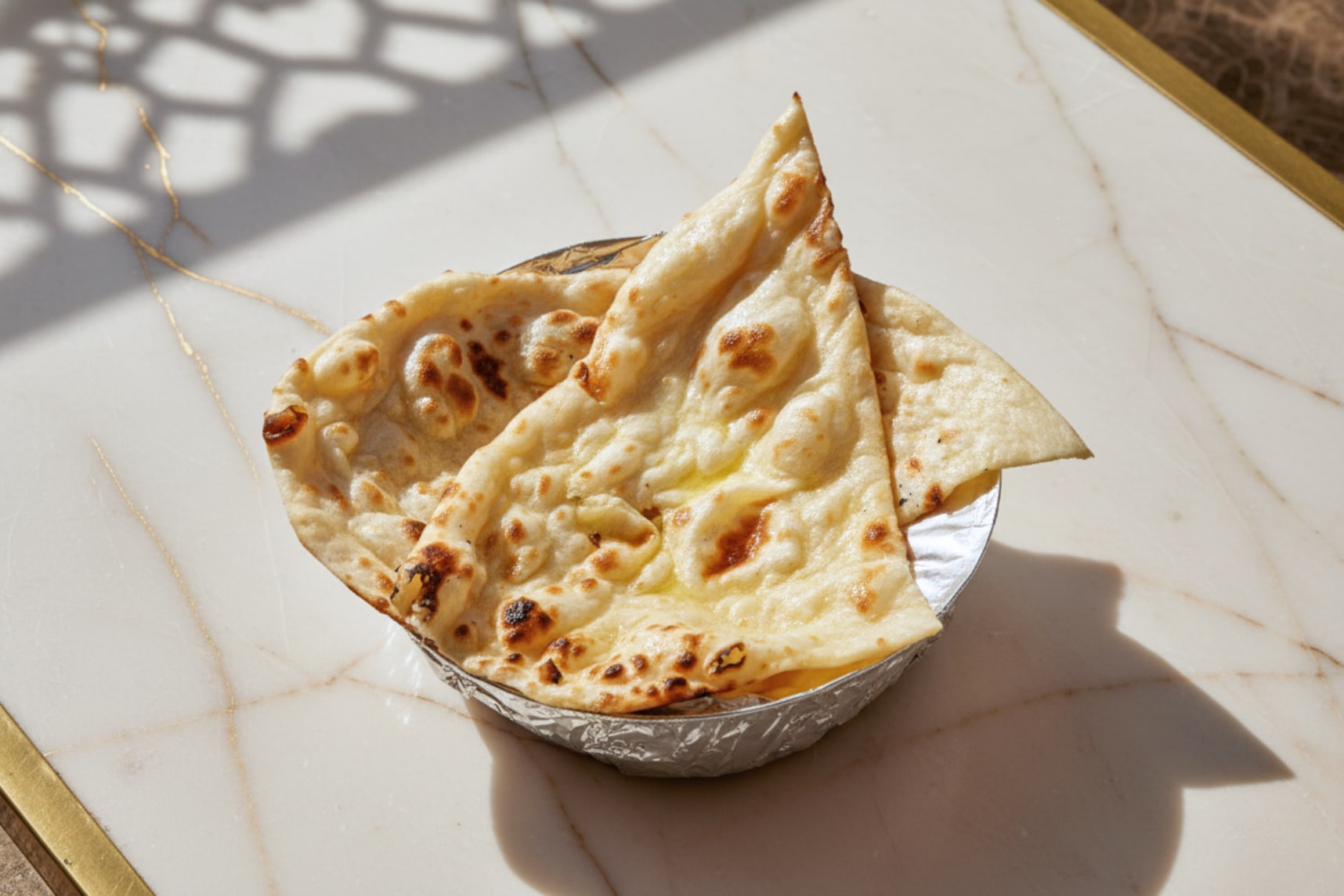 Butter naan, brushed and blistered, torn open on a plate
