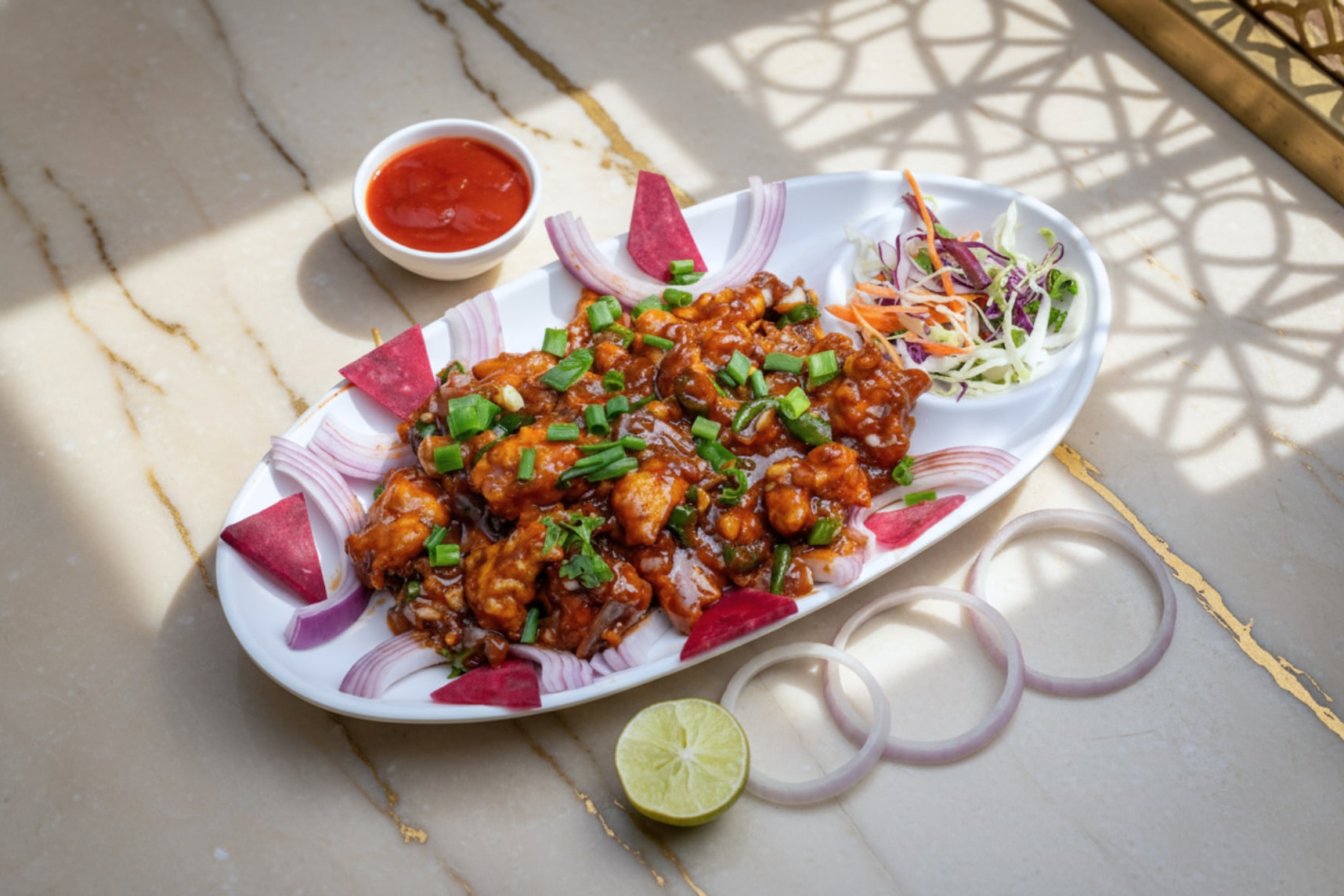 Chicken manchuria in a dark sauce with spring onion