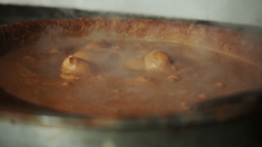 A wide vessel of masala simmering over the fire