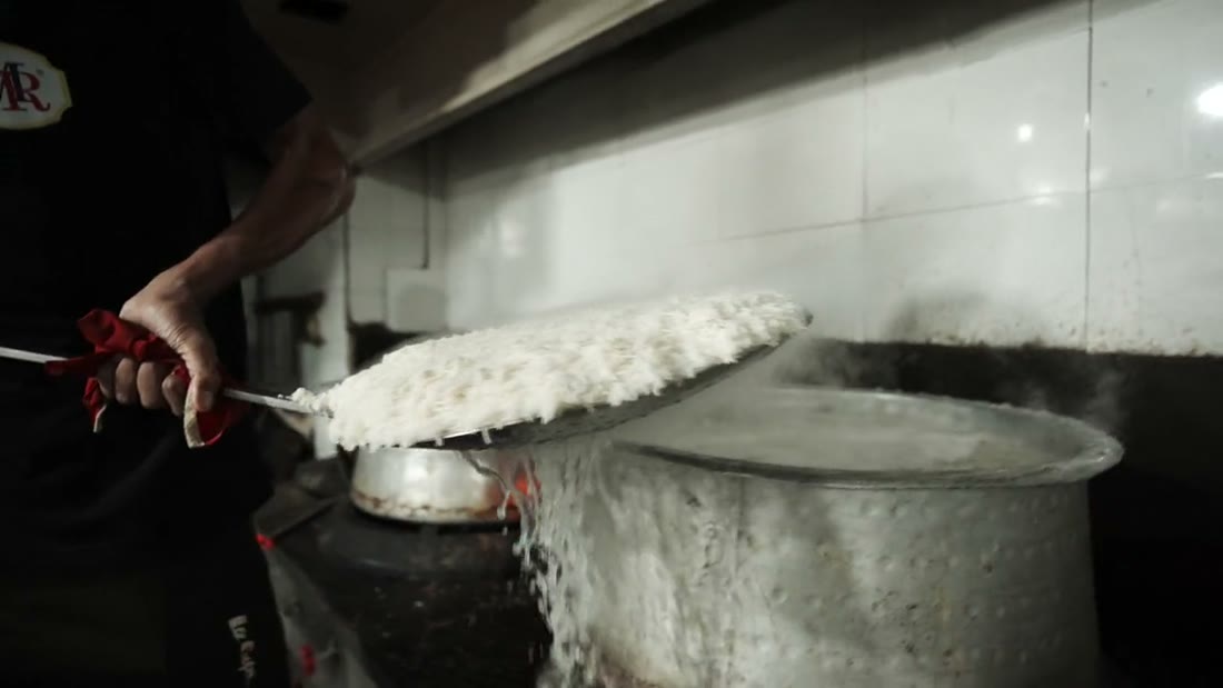 Rice lifted steaming from a cooking pot in a Mehfil kitchen